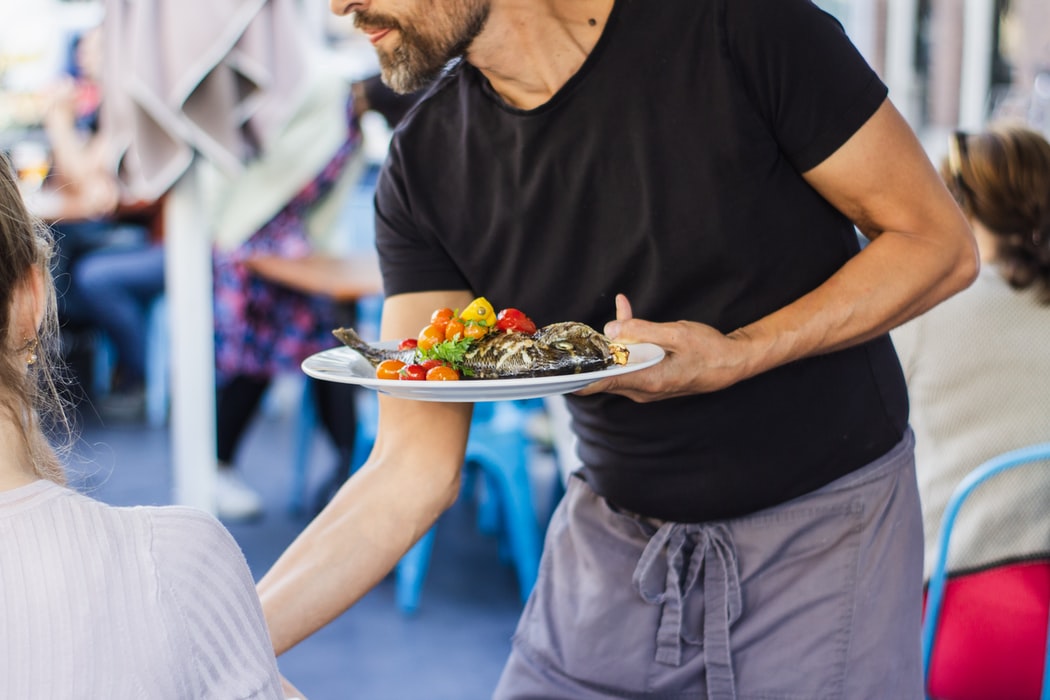 A waiter serving a plate of food to customers