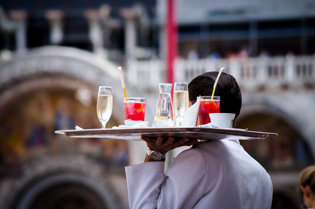 A waiter carry a tray of drinks to a table